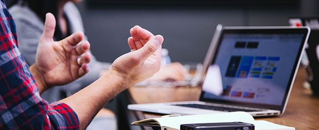 hands gesturing in front of laptop placed on desk